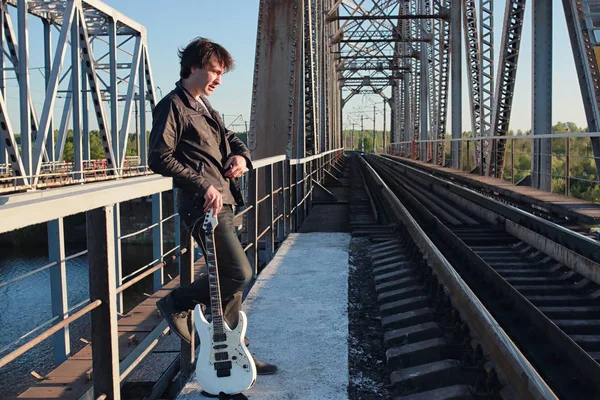 Homem com uma guitarra elétrica na paisagem industrial ao ar livre — Fotografia de Stock