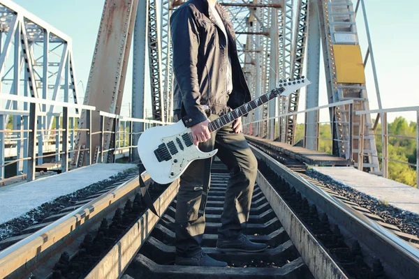 Homem com uma guitarra elétrica na paisagem industrial ao ar livre — Fotografia de Stock