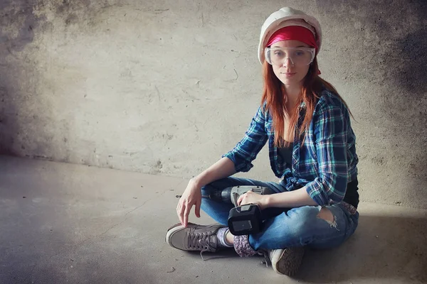 La chica está haciendo reparaciones en el apartamento. Casa mudándose a un nuevo apartamento. El trabajador hace reparaciones, enlucido y taladra la pared . — Foto de Stock