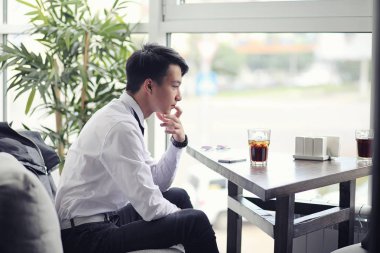 Genç Asyalı işadamı bir kafede bir ortak için bekliyor. Bu