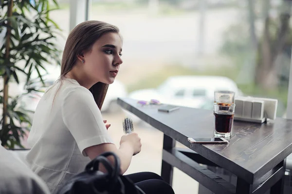 Una ragazzina in un bar. La ragazza è seduta sul divano e parla al telefono . — Foto Stock