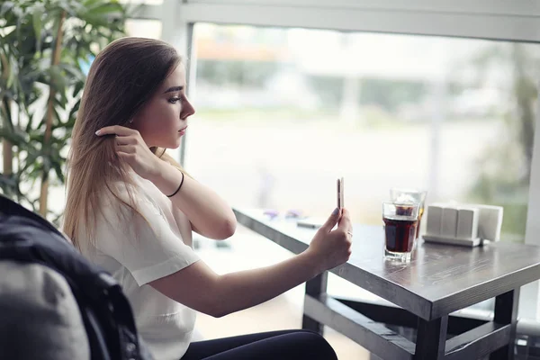 Una ragazzina in un bar. La ragazza è seduta sul divano e parla al telefono . — Foto Stock