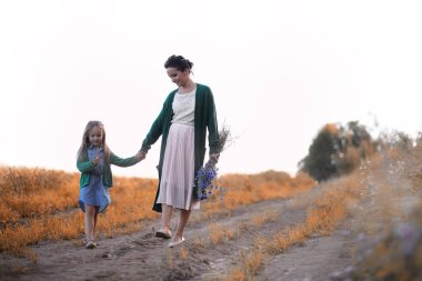 Anne ve kızı yolda yürüyor.