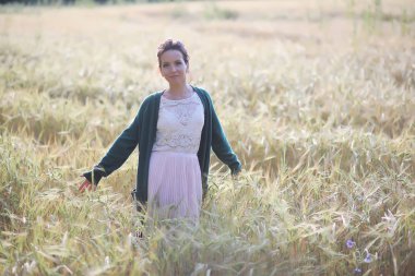 Genç anne yürüyerek buğday alanları içerisinde