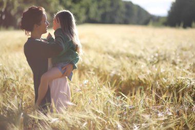 Genç anne yürüyerek buğday alanları içerisinde
