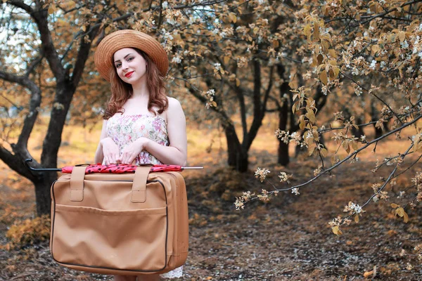 Девушка с кожаным чемоданом для путешествий в осеннем парке на прогулке — стоковое фото