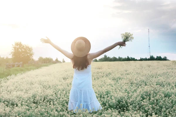 Ragazza in abito bianco in un campo di fiori gialli in fiore — Foto Stock