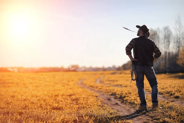 A man cowboy hat and a loso in the field. American farmer in a f — Stock Photo, Image