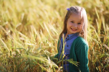 Genç anne yürüyerek buğday alanları içerisinde