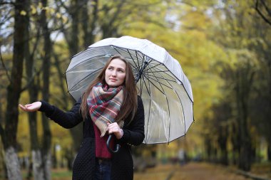 Genç kız sonbahar parkında yürüyüş yapıyor. 