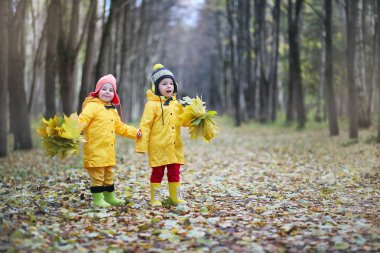 Çocuklar sonbahar parkında yürüyor. 