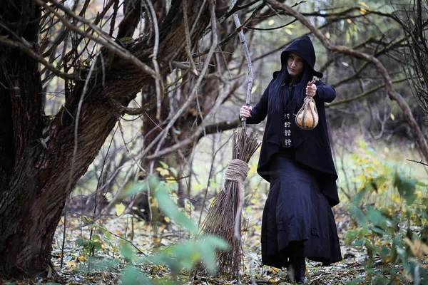 En kvinna i en häxa kostym i en skog — Stockfoto