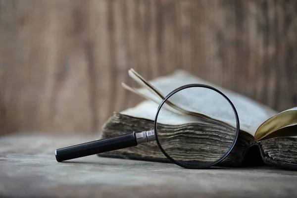 Libros antiguos sobre una mesa de madera y lupa — Foto de Stock