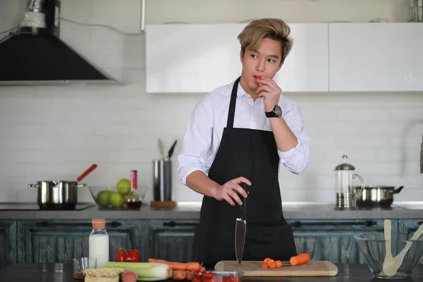 Asian cook in the kitchen prepares food in a cook suit