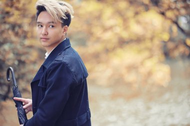 Sonbahar yağmurlu hava ve bir şemsiye ile genç bir adam