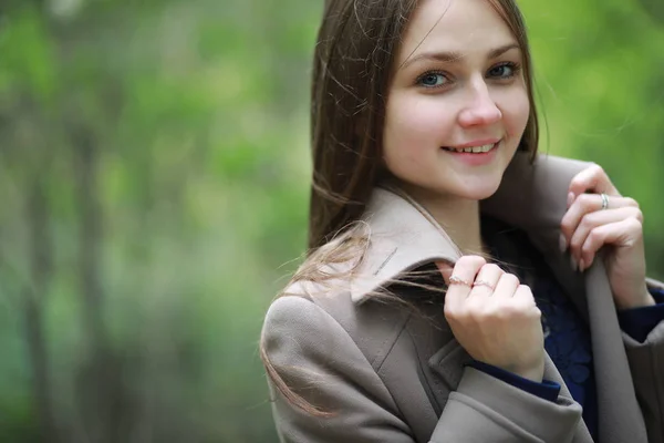 Jeune fille dans un manteau dans un parc de printemps — Photo