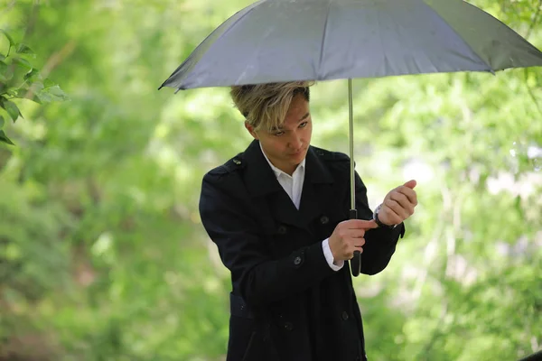 Spring rainy weather and a young man with an umbrella