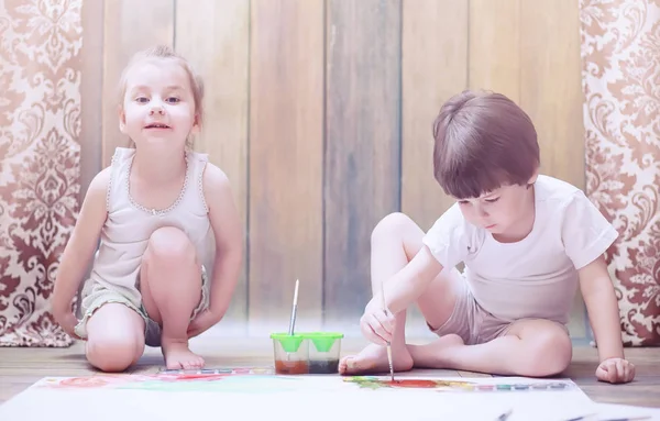 Niños pequeños pintan en una hoja grande de papel —  Fotos de Stock