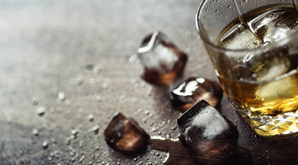 Whisky avec glace avec un verre. Cubes de glace sur une table en bois un — Photo