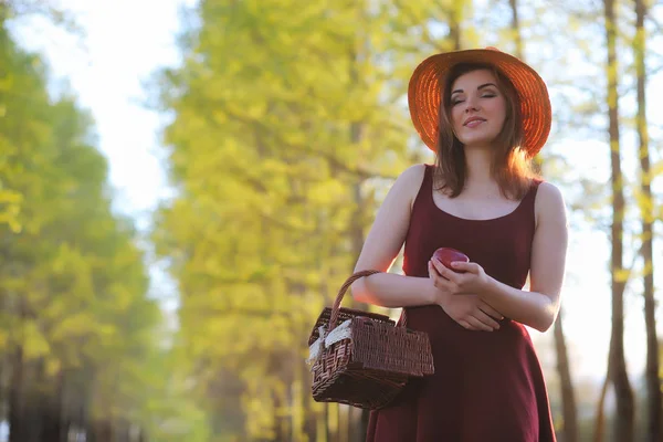 Parkta bir yürüyüş üzerinde şapkalı bir kız. Bir kızla bir sepet yürüyüş