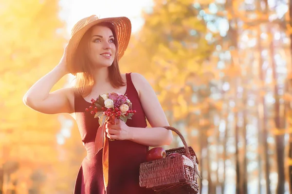 Parkta bir yürüyüş üzerinde şapkalı bir kız. Bir kızla bir sepet yürüyüş