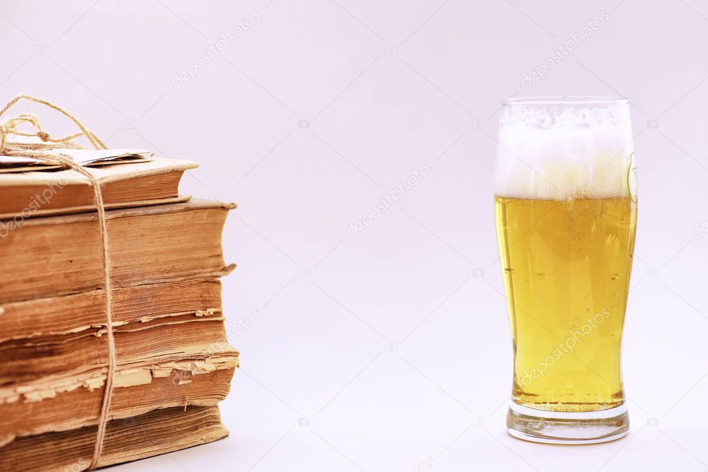 A stack of vintage books and a mug of light beer