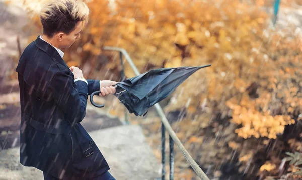 Sonbahar yağmurlu hava ve bir şemsiye ile genç bir adam — Stok fotoğraf