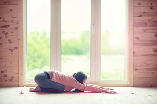 Flicka i yogaställningarna på golvet — Stockfoto