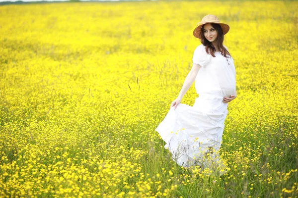 Schwangere in einem Kleid in einem Blumenfeld — Stockfoto