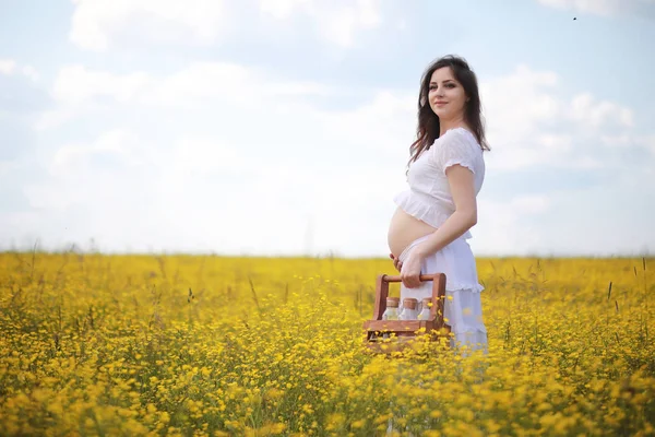 Donna incinta in un vestito in un campo di fiori — Foto Stock