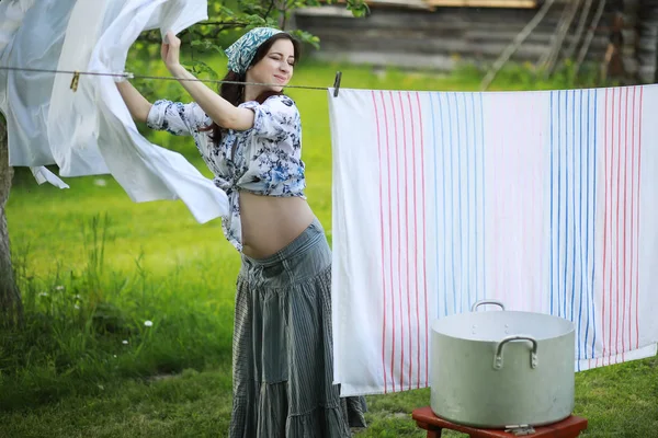 Pregnant woman hanging wash clothes on the rope for drying — Stock Photo, Image