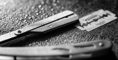 Tehlikeli bir ustura ve masanın üzerinde metal bir bıçak. Mens tıraş 