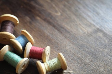 Ahşap arka plan üzerinde dikiş ipliği. Bobin iş parçacığı kümesi 