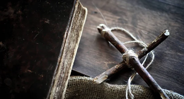 Livro velho religioso em uma mesa de madeira. Uma cruz religiosa amarrado sagacidade — Fotografia de Stock