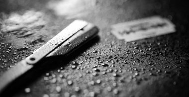 Tehlikeli bir ustura ve masanın üzerinde metal bir bıçak. Mens tıraş 