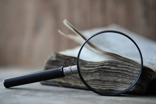 Libros antiguos sobre una mesa de madera y lupa — Foto de Stock