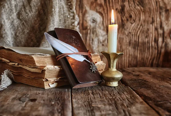 Пір'я і книжковий роман поруч зі свічкою — стокове фото