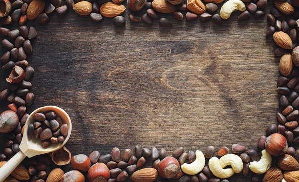 Olika nötter på ett träbord. Ceder, cashew, hasselnöt, walnu — Stockfoto