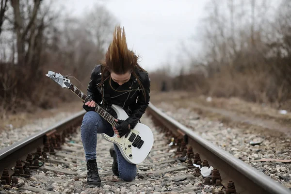 Uma menina músico de rock em uma jaqueta de couro com uma guitarra — Fotografia de Stock