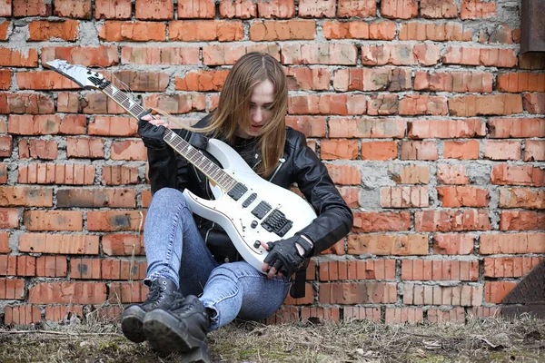 Uma menina músico de rock em uma jaqueta de couro com uma guitarra — Fotografia de Stock