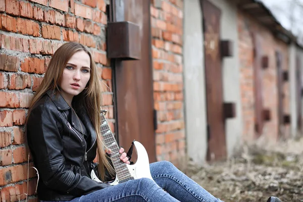 Uma menina músico de rock em uma jaqueta de couro com uma guitarra — Fotografia de Stock