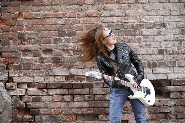 Uma menina músico de rock em uma jaqueta de couro com uma guitarra — Fotografia de Stock