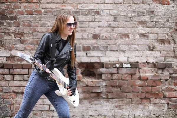 Una chica músico de rock en una chaqueta de cuero con una guitarra — Foto de Stock