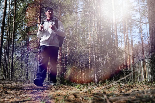 Un hombre es un turista en un bosque de pinos con una mochila. Un tr senderismo — Foto de Stock