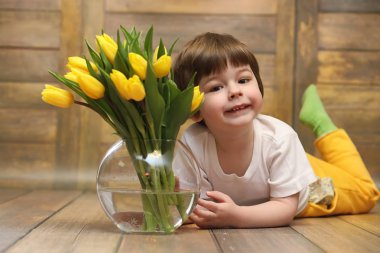Bir buket Sarı laleler ile küçük bir çocuk. Bir çocuk bir hediye ile