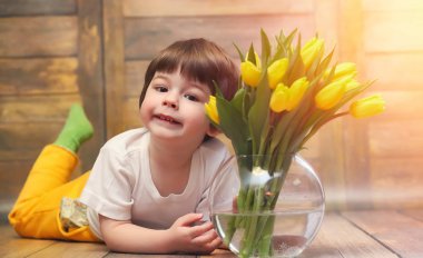 Bir buket Sarı laleler ile küçük bir çocuk. Bir çocuk bir hediye ile