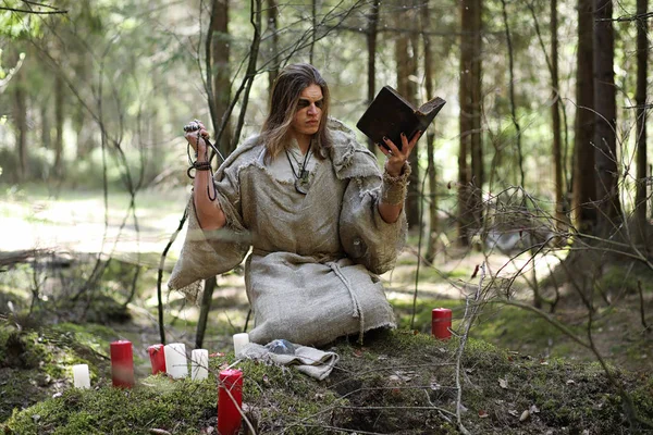 Un uomo con una tonaca trascorre un rituale in una foresta oscura — Foto Stock