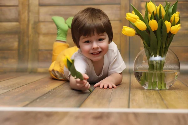 Un niño pequeño con un ramo de tulipanes amarillos. Un chico con un regalo —  Fotos de Stock