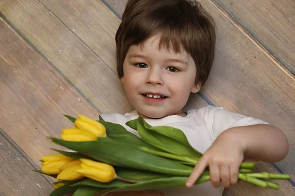 A small child with a bouquet of yellow tulips. A boy with a gift — Stock Photo, Image