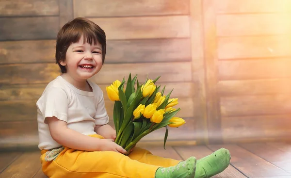 Bir buket Sarı laleler ile küçük bir çocuk. Bir çocuk bir hediye ile — Stok fotoğraf